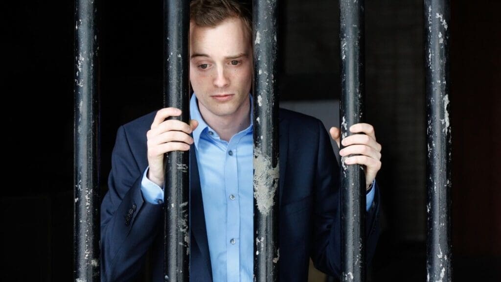 Man Looking Through Jail Bars in Despair